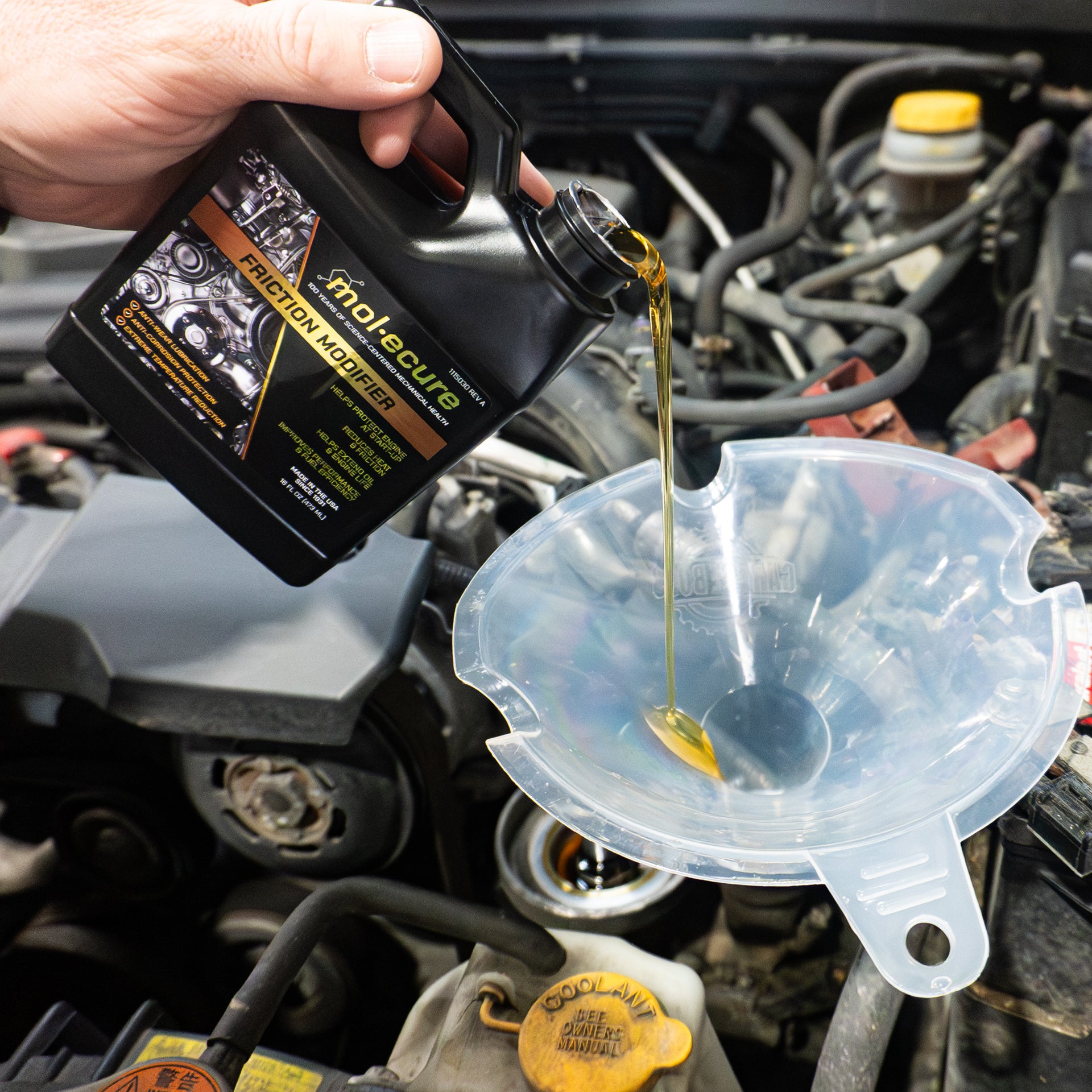 A hand pours a container of Molecure™ Catalytic Restore Emission Treatment into a clear funnel above a car engine.